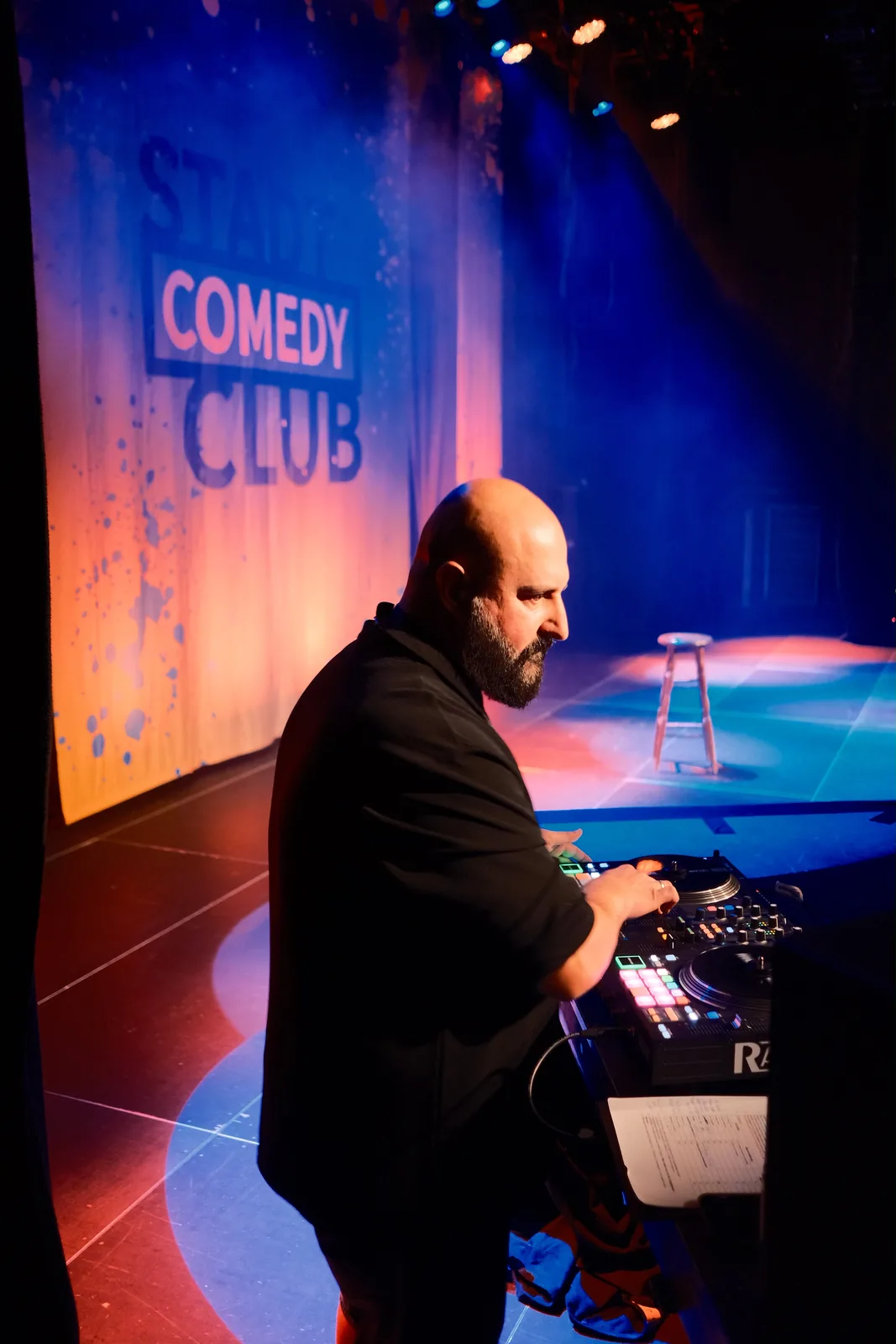 Der DJ am Pult neben der Bühne, im Hintergrund das Banner des StadtComedyClub.